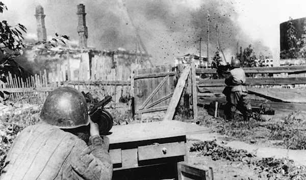 Standing in the backyard of an abandoned house in the outskirts of the besieged city of Leningrad, a rifleman of the Red Army aims and fires his machine gun at German positions, on December 16, 1942 (AP Photo)