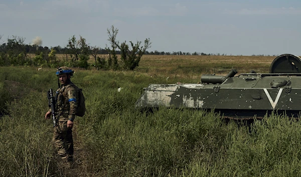 A soldier of Ukraine's 3rd Separate Assault Brigade goes past a Russian-destroyed APC near Bakhmut, the site of fierce battles with the Russian forces in Donetsk, Sept. 4, 2023 (AP)