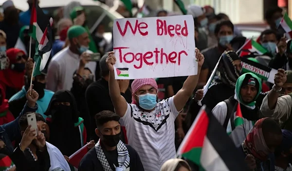 A demonstrator holds a placard as they march through the city Centre in Cape Town, on 12 May 2021 during a protest against Israeli attacks on Palestinians in Gaza (AFP via Getty Images)