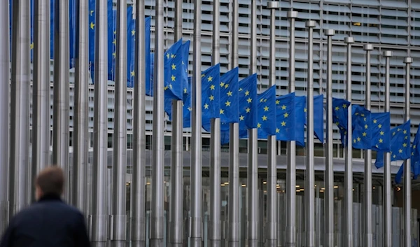 A man walks past European Union flags at half staff, in front of European Union headquarters in Brussels, Thursday, Dec. 28, 2023 (AP)