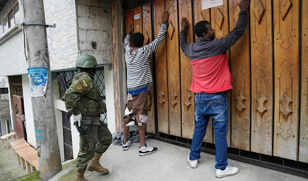 Residents stand still with their hands up for a soldier who will search them as the military patrols the south side of Quito, Ecuador, Friday, Jan. 12, 2024. (AP)