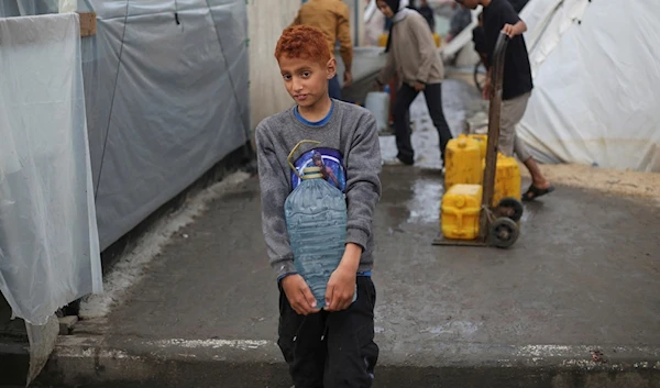 Displaced Palestinian carries water in a makeshift tent camp in Rafah, Gaza Strip, occupied Palestine, Thursday, Dec. 28, 2023. (AP)