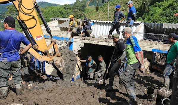 Residents and rescue workers look for survivors at a rural school buried by a landslide caused by heavy rains in Taparto, Colombia, Thursday, July 14, 2022 (AP)