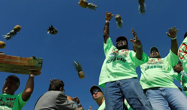 International Longshoremen's Association union members toss Del Monte company pineapples into the Delaware River following a Labor Day parade in Philadelphia, Monday, Sept. 6, 2010.(AP)