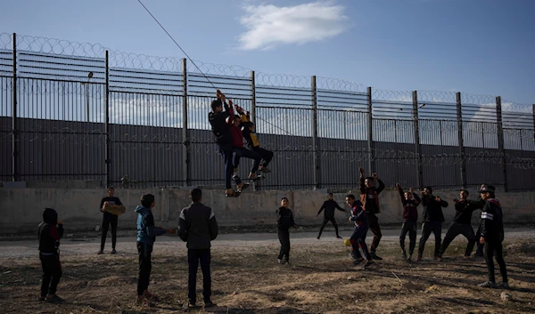 Palestinians displaced by the Israeli bombardment of the northern Gaza Strip play next to the border with Egypt, in Rafah, southern Gaza, Sunday, Jan. 14, 2024.(AP)