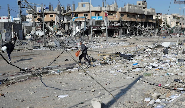 Palestinians walk through destruction by the Israeli bombardment in the Nuseirat refugee camp in Gaza Strip, Tuesday, Jan. 16, 2024(AP)