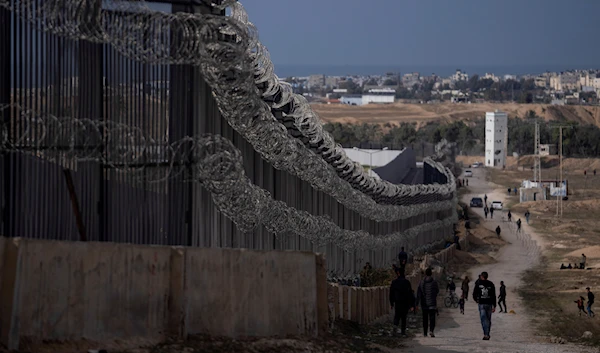 Palestinians displaced by the Israeli bombardment of the Gaza Strip walk next to the border with Egypt, in Rafah, southern Gaza, Sunday, Jan. 14, 2024.(AP)