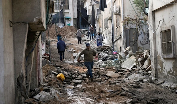 Palestinians walk through the aftermath of the Israeli military raid on Nur Shams refugee camp in the West Bank, Wednesday, Dec. 27, 2023 (AP Photo/Majdi Mohammed)