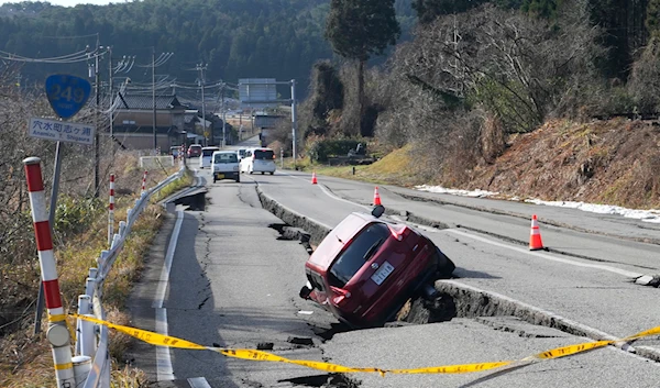 A car is trapped at a partially collapsed road caused by a powerful earthquake near Anamizu Town, Ishikawa Prefecture Tuesday, Jan. 2, 2024. (AP)