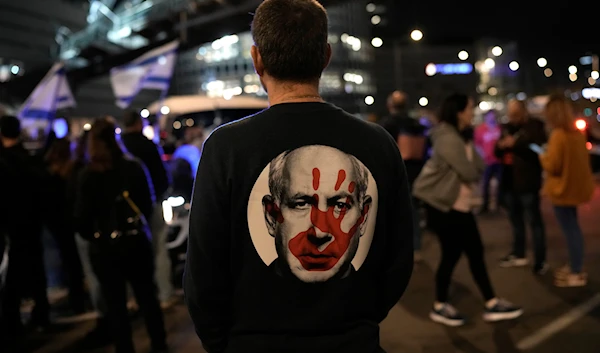 A protester wears a shirt depicting Israeli Prime Minister Benjamin Netanyahu during a demonstration to demand the release of the captives taken during Operation al-Aqsa Flood, in 'Tel Aviv', occupied Palestine, January 20, 2024 (AP)