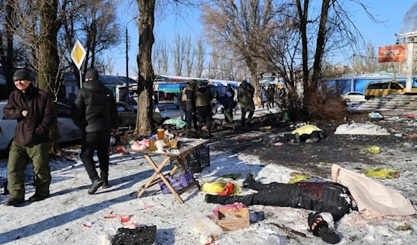 People walk past bodies of victims killed during the Ukrainian shelling on the Donetsk, Sunday, Jan. 21, 2024.