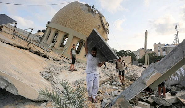 A man retrieves a solar panel from a mosque destroyed in an Israeli airstrike against the city of Khan Younis, in the southern Gaza Strip, on October 8, 2023 (AP)