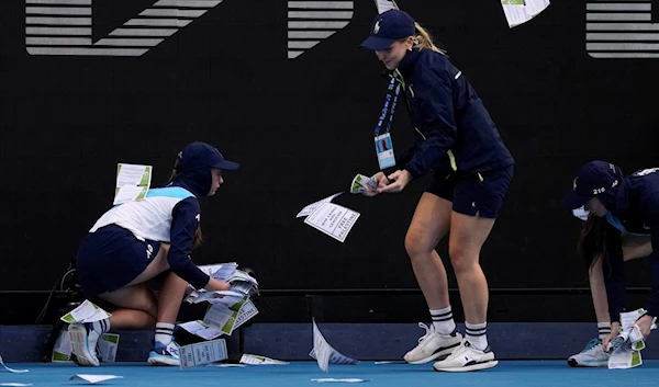 Ball kids pickup "free Palestine" leaflets thrown onto Margaret Court Arena at Melbourne Park, Melbourne, Australia, Monday, Jan. 22, 2024 (AP)