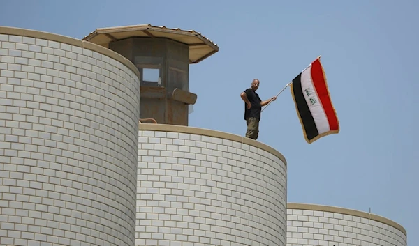 A man waves the Iraqi flag above the Iraqi parliament building in Baghdad, Iraq, Saturday, July 30, 2022.(AP)