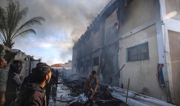 Palestinians try to extinguish a fire at a building of an UNRWA vocational training center which displaced people use as a shelter, after being targeted by Israeli tank shill in Khan Younis, southern Gaza Strip, Wednesday, Jan. 24, 2024. (AP)