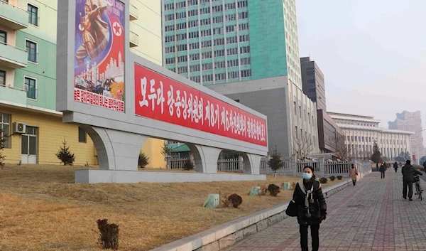 Pyongyang citizens walk past a banner reading "Adorn the 75th birthday of the DPRK and the 70th anniversary of the war victory with high political enthusiasm and shining labor achievements!" in Pyongyang, DPRK, Monday, Feb. 6, 2023 (AP)