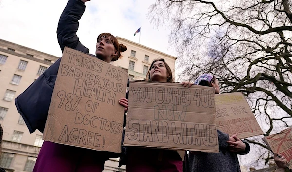 Junior doctors hold placards as they demonstrate outside Downing Street, in London, Monday, March 13, 2023 (AP)