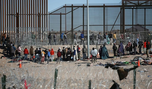 Migrants line up after being detained by U.S. immigration authorities at the U.S. border wall, seen from Ciudad Juarez, Mexico, Wednesday, Dec. 27, 2023 (AP Photo/Christian Chavez)