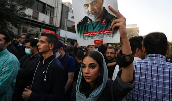 Iranian woman holds up portrait of Late IRGC commander Qassem Soleimani in Tehran, Iran, Sunday, Sept. 25, 2022 (AP)