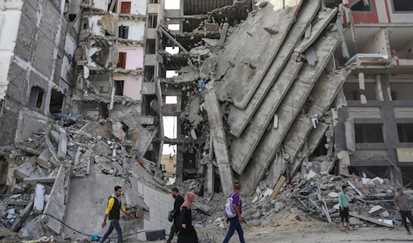 Palestinians walk through destruction in Gaza City on Friday, Nov. 24, 2023 (AP)