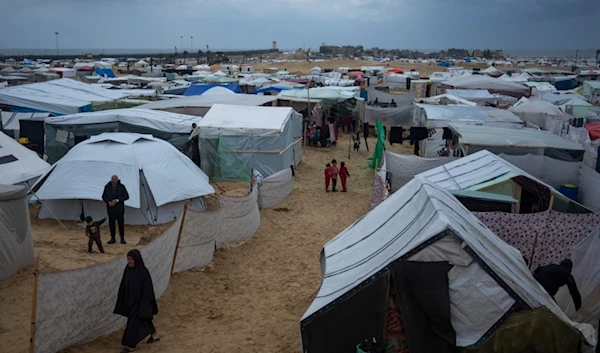 Palestinians displaced by the Israeli air and ground invasion on the Gaza Strip walk through a makeshift tent camp in Rafah on Saturday, Jan. 27, 2024. (AP Photo/Fatima Shbair)