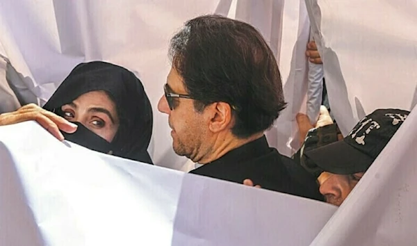 In this file photo, with a white sheet put around them, PTI Chairman Imran Khan and his wife Bushra Bibi arrive at the Lahore High Court. (AFP)