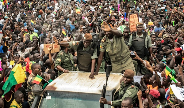 An unidentified representative of the junta waves from a military vehicle as Malians supporting the overthrow of President Ibrahim Boubacar Keita gather to celebrate in the capital Bamako, Mali, August 21, 2020 (AP)