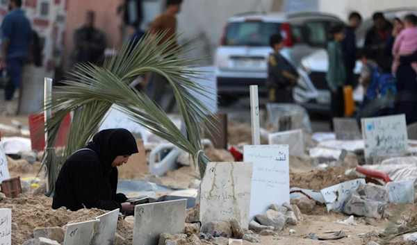 Palestinians visit the graves of people killed in the Israeli bombardment of the Gaza Strip and buried inside the Shifa Hospital grounds in Gaza City, Sunday, Dec. 31, 2023. (AP)