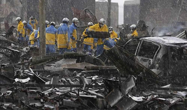 Police officers remove debris from a fire at a market in Wajima, Ishikawa perfecture, Japan, Saturday, Jan 6, 2024.(Kyodo News via AP)