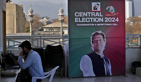 A supporter works on his desk next to a poster of Pakistan's Former Prime Minister Imran Khan displayed at his party office, in Islamabad, Pakistan, Friday, Feb. 9, 2024(AP)