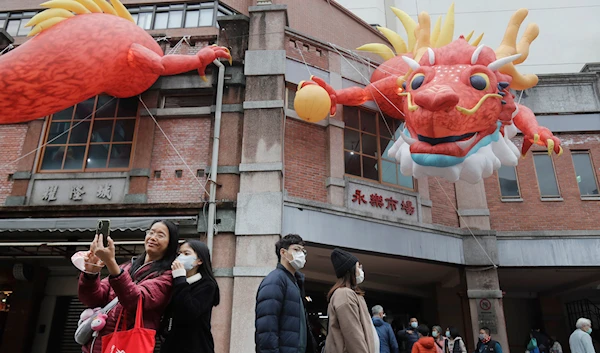 People walk under dragon balloons decorated on a building for the upcoming Lunar New Year celebrations at the Dihua street market in Taipei, Taiwan, Thursday, Feb. 8, 2024. (AP)