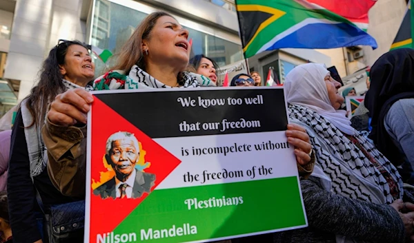 A woman holds a Palestinian flag with a Picture of former South Africa's president Nelson Mandela, during a protest outside the South African consulate in Beirut, Lebanon, Friday, Jan. 19, 2024. (AP)