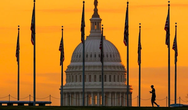 An early morning pedestrian is silhouetted against sunrise as he walks through the U.S. Flags on the National Mall and past the US Capitol Building in Washington Monday, Nov. 7, 2022. (AP Photo)