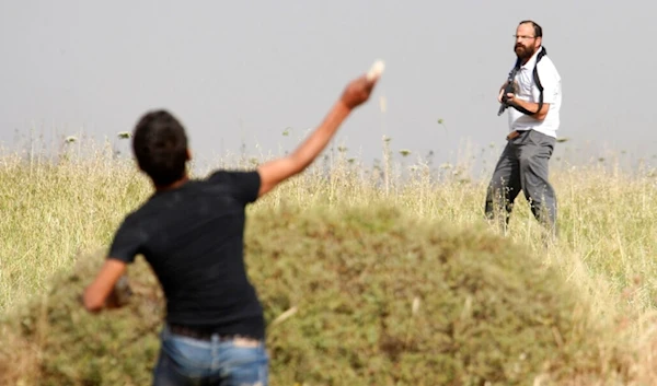 In this May 19, 2012 file photo, a Palestinian throws a stone at an armed Israeli settler invading a Palestinian village in the occupied West Bank, Palestine. (AP)