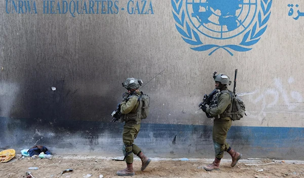 Two Israeli invading soldiers pass by UN premises in Gaza. (AFP)