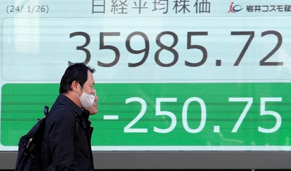 People walk in front of an electronic stock board showing Japan's Nikkei 225 index at a securities firm Friday, Jan. 26, 2024, in Tokyo (AP)