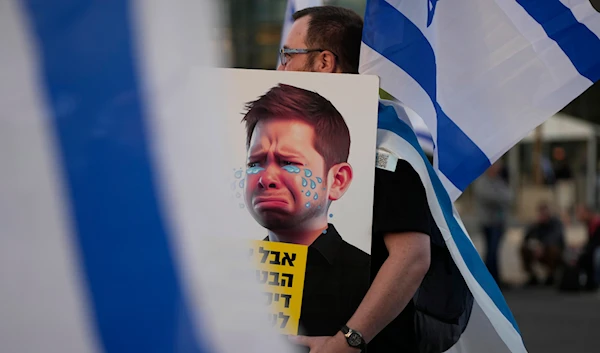 An Israeli protesting plans by Prime Minister Benjamin Netanyahu's far-right government carries a caricature of son Yair Netanyahu on April 1, 2023. (AP)