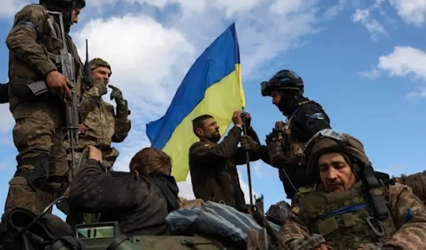 Ukrainian soldiers adjust their national flag atop a personnel armored carrier on a road near Lyman, in the Donetsk region, on Oct. 4, 2022. (AFP via Getty Images)