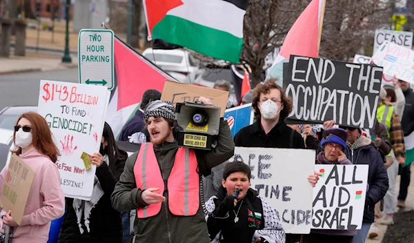 Pro-Palestinian demonstrators display signs while marching during a protest held to call for a cease fire in the war in Gaza, Sunday, Feb. 11, 2024, in Braintree, Massachusetts. (AP)