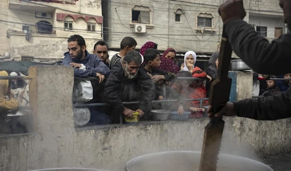 Forcibly displaced Palestinians due to the ongoing Israeli genocide line up for a free meal in Rafah, Gaza Strip, Thursday, Dec. 21, 2023. (AP)