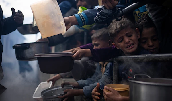 Palestinians line up for a free meal in Rafah, Gaza Strip, February 16, 2024 (AP)