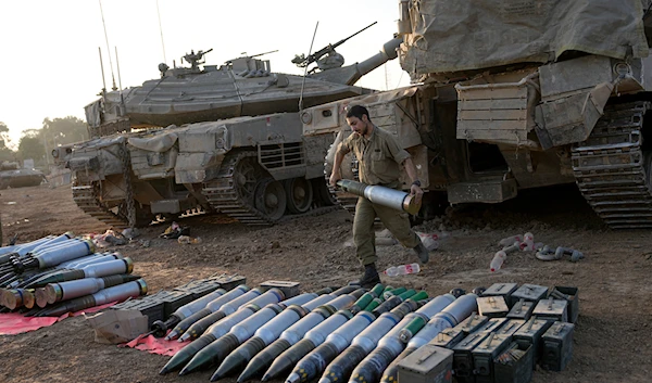 IOF troops load shells onto a tank at a staging area in southern occupied Palestine near the border with Gaza on Sunday, Dec. 31, 2023(AP)