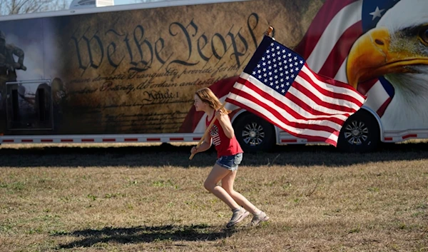 Lola Lee, from New Mexico, runs with a U.S. flag during a "Take Our Border Back" convoy and rally, Saturday, Feb. 3, 2024, in Quemado, Texas. (AP Photo/Eric Gay)