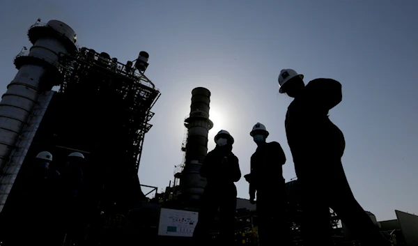 Saudi Aramco engineers walk in front of a gas turbine generator at Khurais oil field during a tour for journalists, outside of Riyadh, Saudi Arabia on June 28, 2021. (AP)