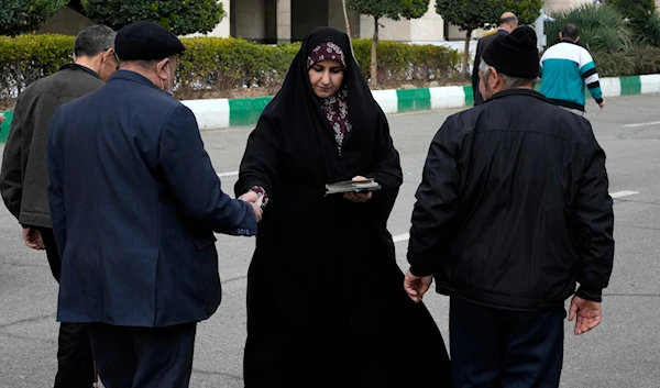 A woman distributes electoral leaflets of a group of candidates for the March 1, election of Assembly of Experts in Tehran, Iran, Friday, Feb. 23, 2024.(AP)