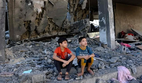 Palestinian children sitting on the rubble of a residential building destroyed by an Israeli airstrike (AFP via Getty Images)