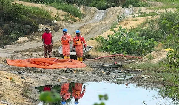 In this grab taken from video, workers stand by a container to collect oil spill waste from an oil spill at a Shell facility in Ogoniland, Nigeria, June 16, 2023. (AP)