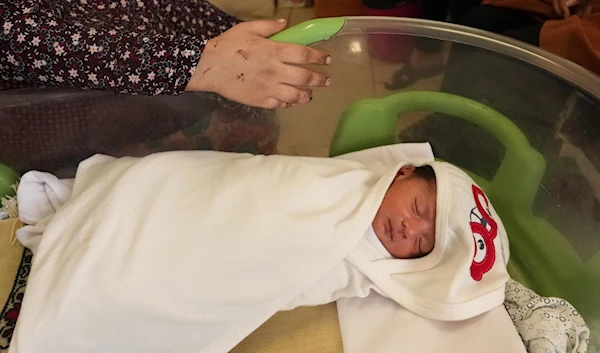 A Palestinian newborn and a woman's injured hand inside the neo-natal department of al-Shifa hospital in Gaza, October 26, 2023. (Bisan Owda for UNFPA)