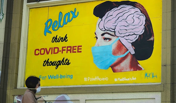 A woman wears a face mask while walking under a sign that reads "Relax think COVID-free thoughts" during the coronavirus outbreak in San Francisco, Saturday, May 23, 2020.(AP)