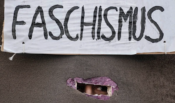 A protestor looks out of a box with the writing 'Fascism' at a demonstration against the AfD party and right-wing extremism in Berlin, Germany, Saturday, Feb. 3, 202(AP)